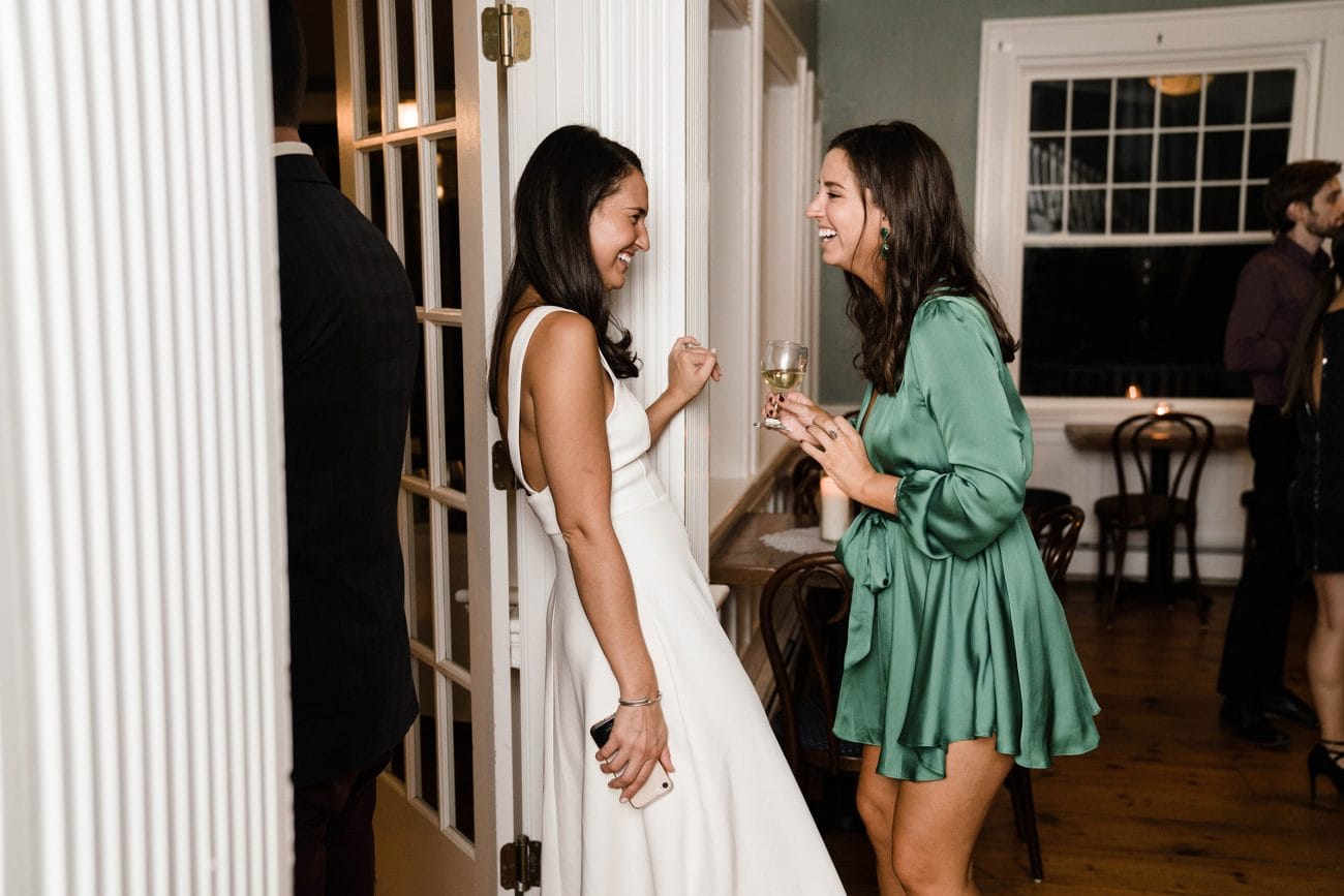 A best of Boston wedding photograph of a bride talking and laughing with her friend during their rehearsal dinner in Boston