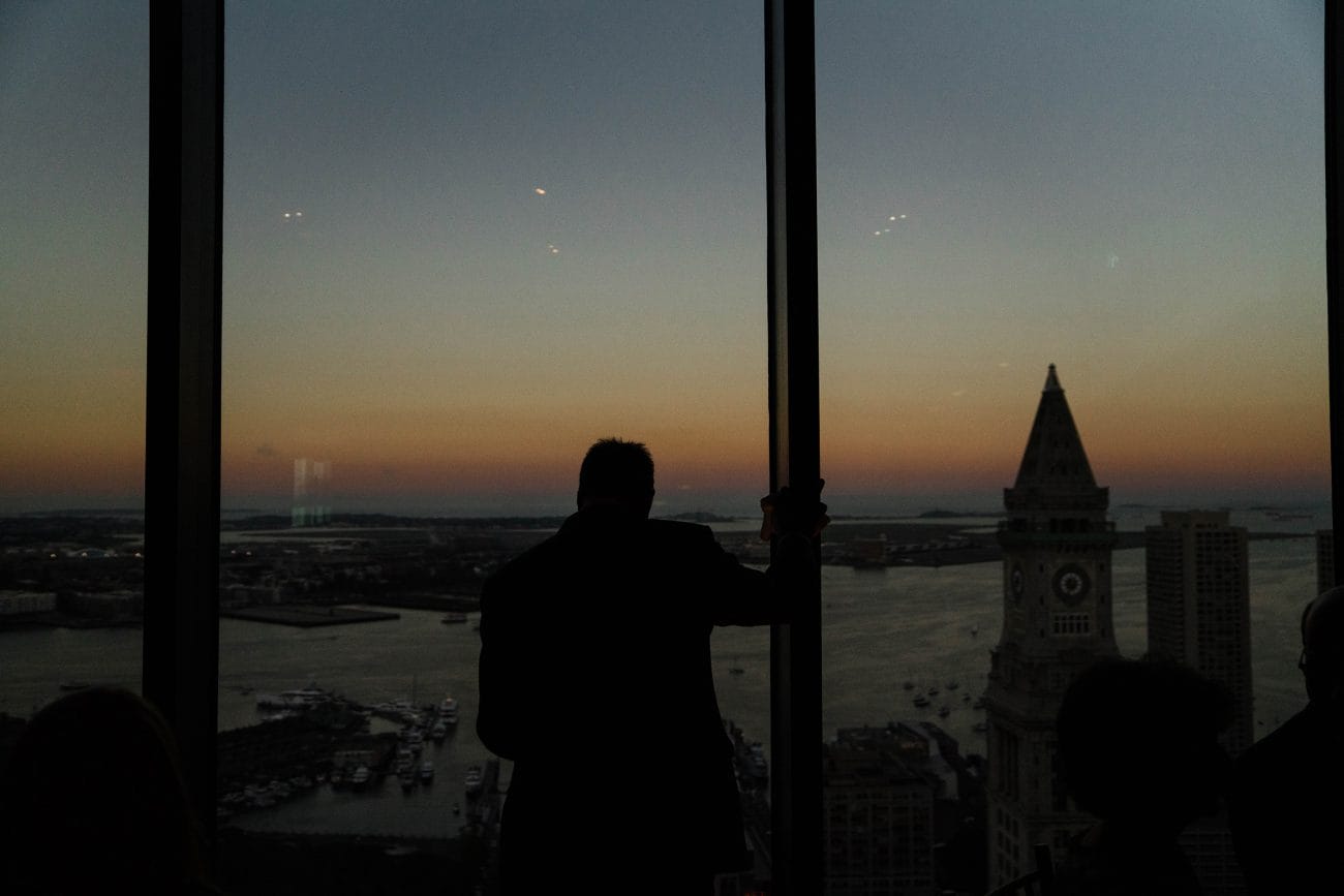 A best of Boston wedding photograph of a wedding guest admiring the view and sunset during a State Room wedding in Boston