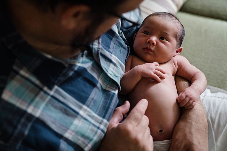 A best of Boston family session of a dad holding his newborn daughter during in home lifestyle newborn session in Boston