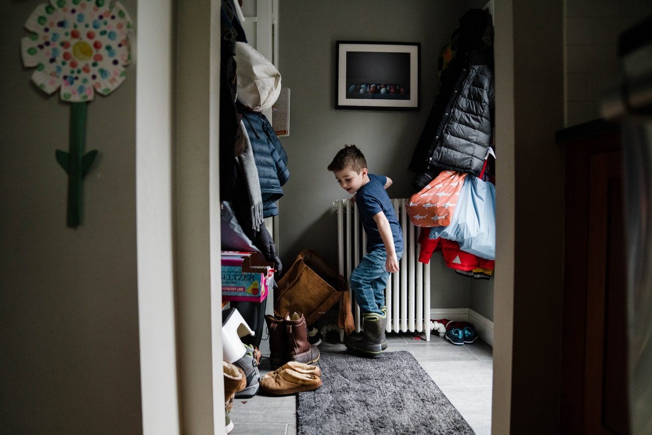 A best of Boston family photograph of a boy putting on his boots to go outside during an in home family session in Boston