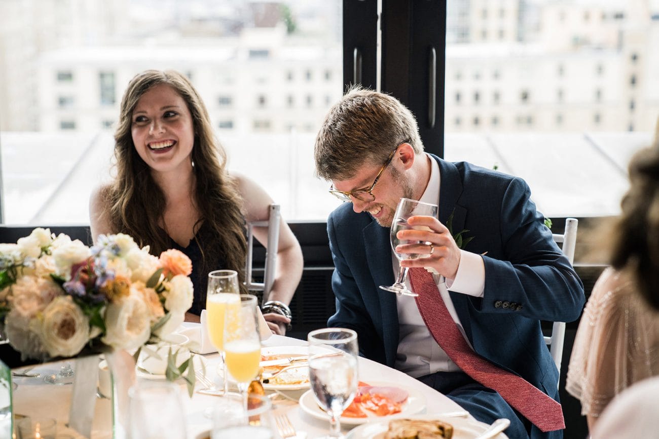 A best of Boston wedding photograph of a groom laughing during the wedding toasts at his Taj Boston rooftop wedding