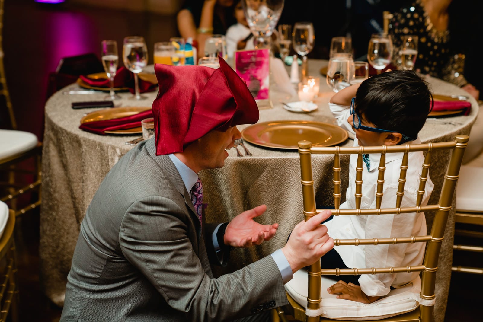 A best of Boston wedding photograph of a wedding guest with a towel on his head to entertain a child during an Indian American wedding in Providence, RI