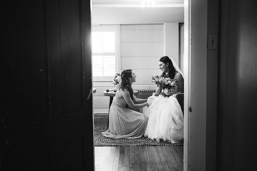 A documentary photograph of a bride and her friend talking moments before she walks down the aisle at her Boston wedding