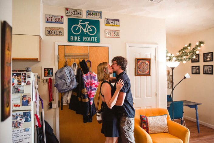 A documentary photograph of a couple kissing at home before they leave for their date night engagement session in Boston