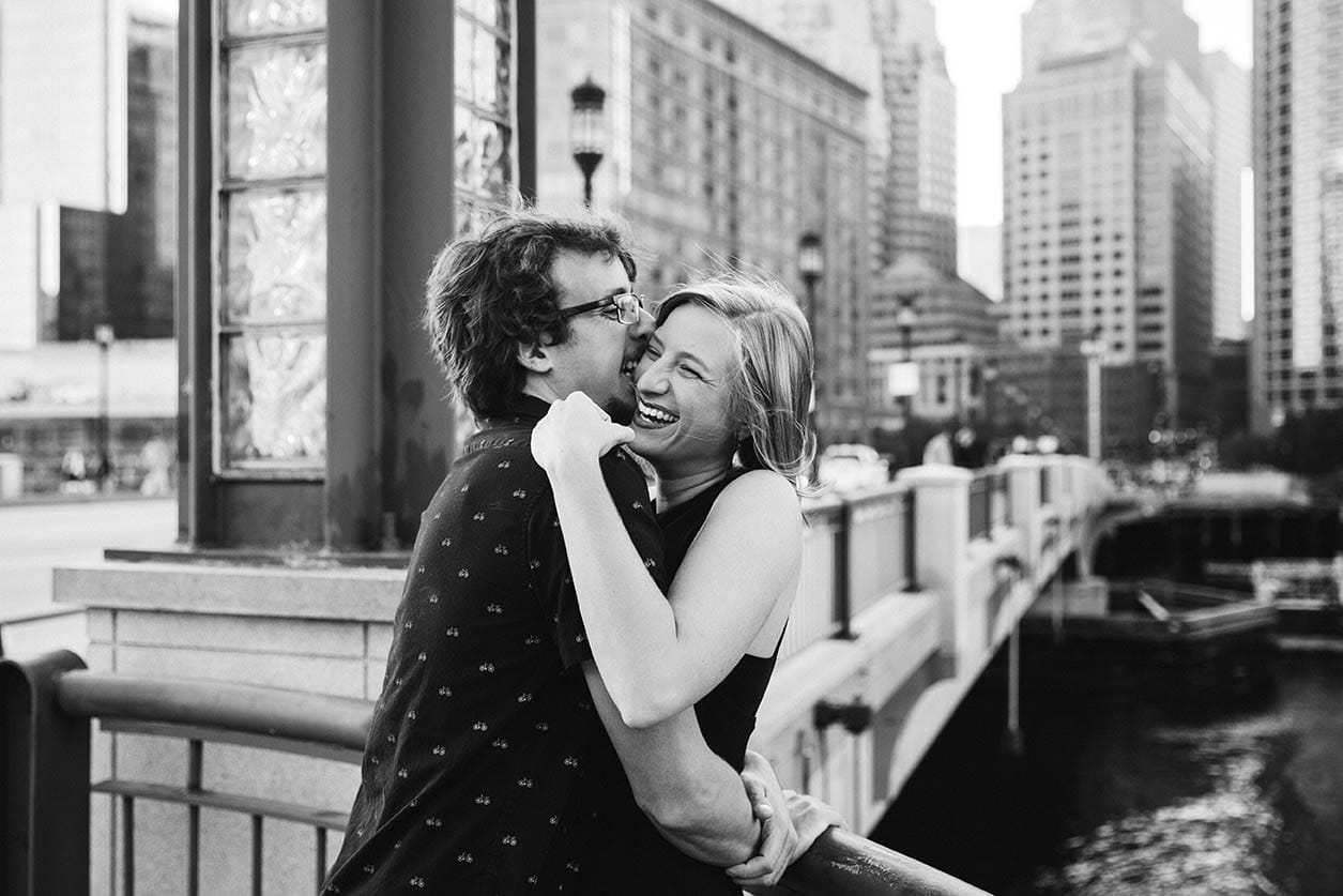 A documentary portrait of a couple hugging and laughing during their Boston Engagement session in Boston's seaport district