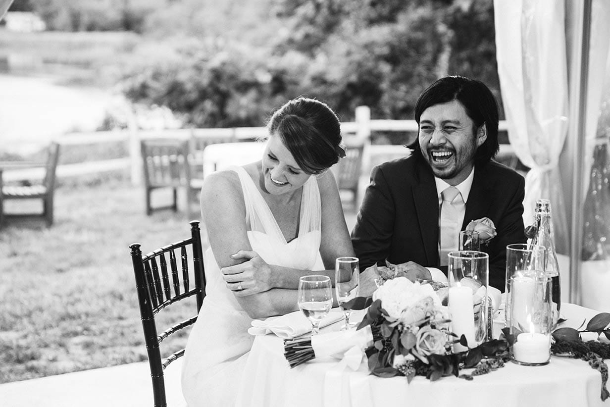 A documentary photograph of a couple laughing during the speeches at their Boston Wedding