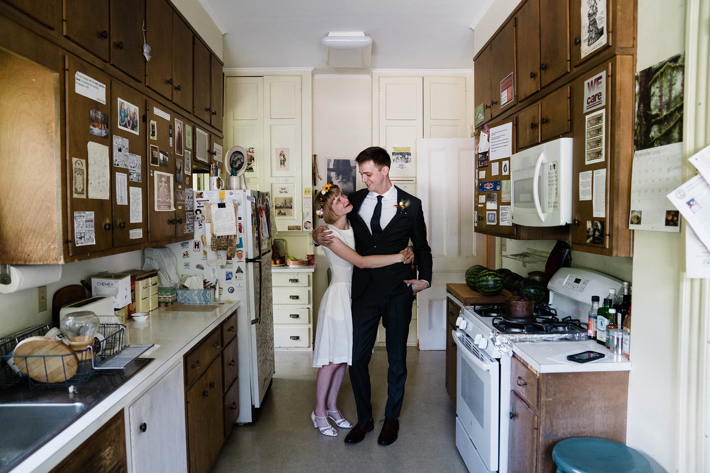 A documentary photograph featured in the best of wedding photography of 2019 of a couple hugging in their kitchen during an in home wedding.