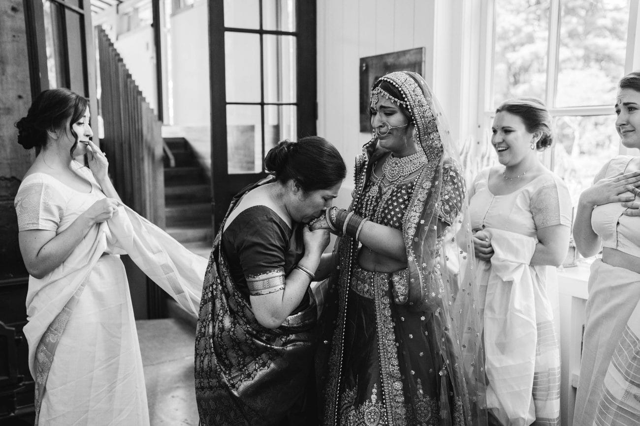A documentary photograph featured in the best of wedding photography of 2019 of a mom kissing her daughters hand as she gets ready for her Indian wedding ceremony