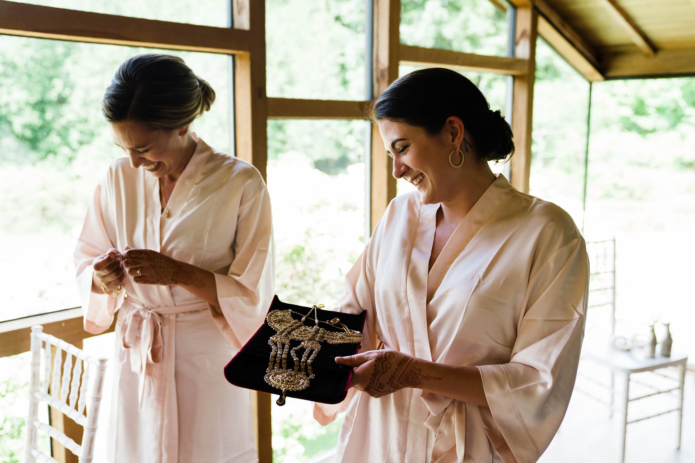 A documentary photograph featured in the best of wedding photography of 2019 showing bridesmaids laughing while helping a bride get ready for her Indian wedding ceremony