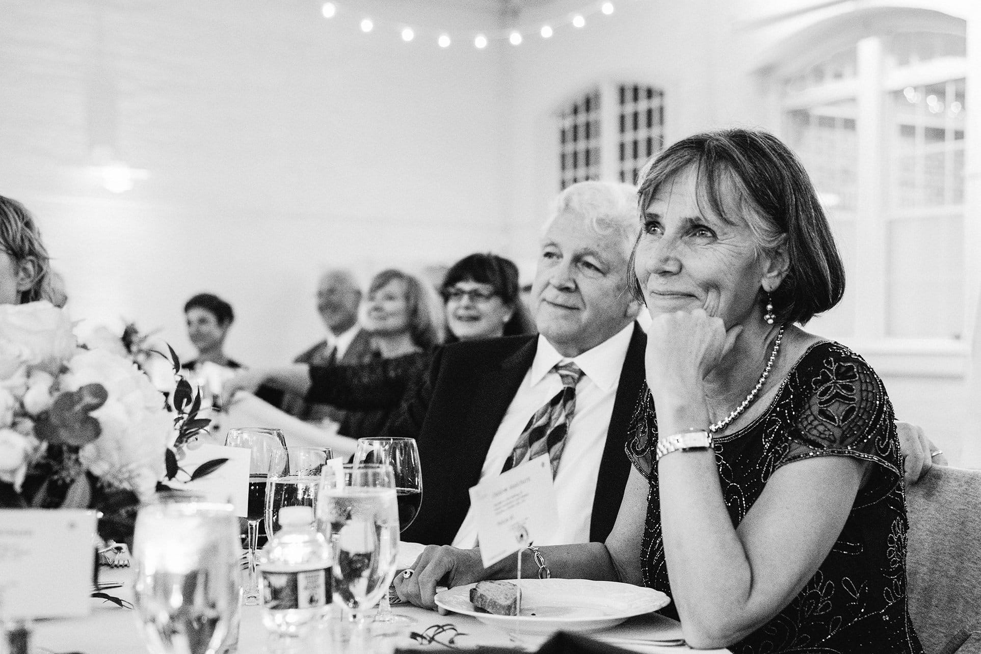 A documentary photograph featured in the best of wedding photography of 2019 showing a mother of the groom smiling during the wedding toasts.