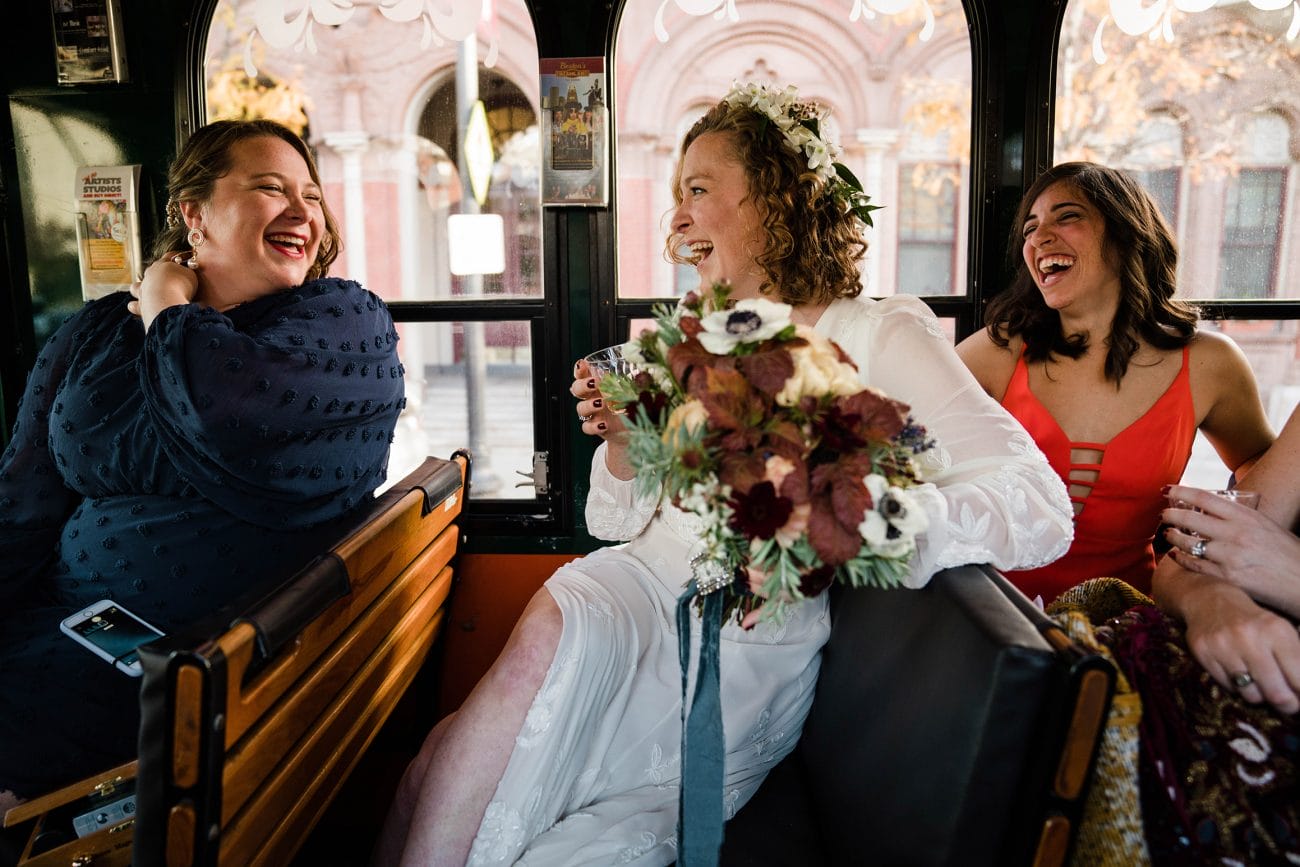 A documentary photograph featured in the best of wedding photography of 2019 showing a bride and her friends laughing on a trolley on the way to their wedding ceremony