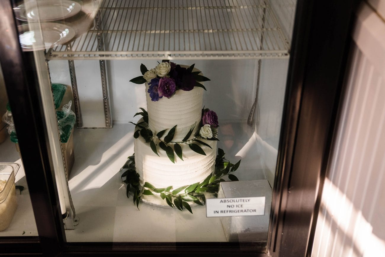 A documentary photograph featured in the best of wedding photography of 2019 showing a wedding cake in the fridge during an outdoor summer wedding