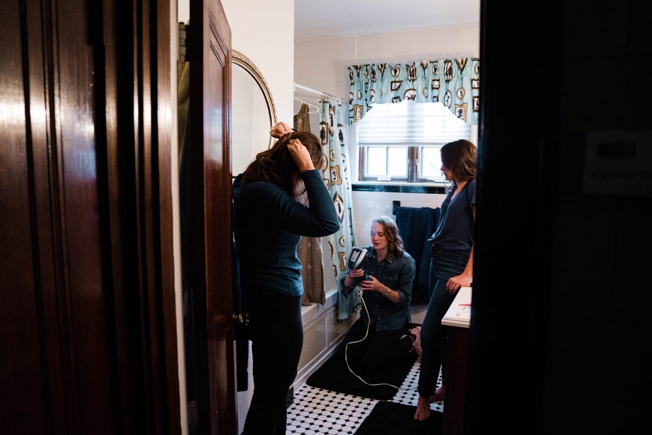 A documentary photograph featured in the best of wedding photography of 2019 showing a bridesmaid steaming a dress while getting ready