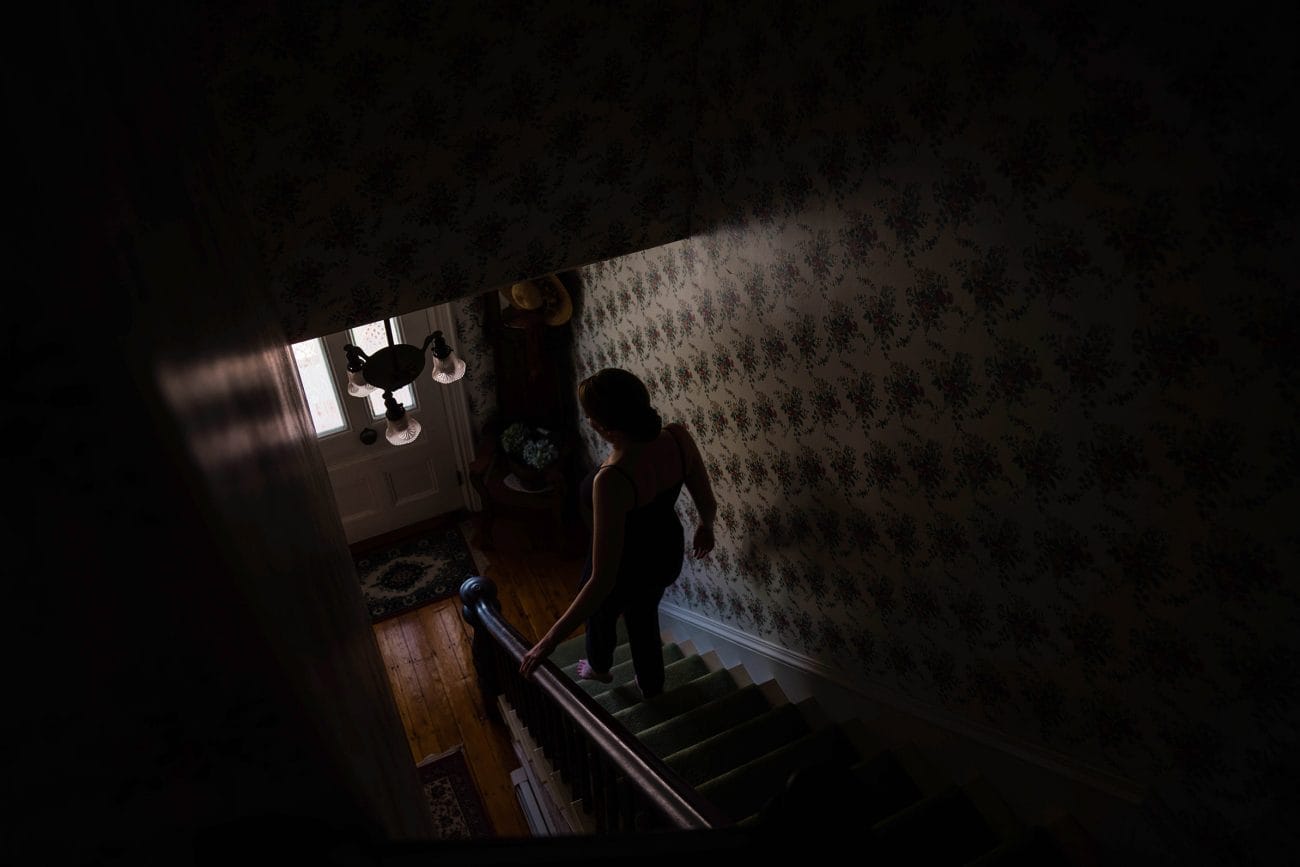 A documentary photograph featured in the best of wedding photography of 2019 showing a bride walking down the stairs at home