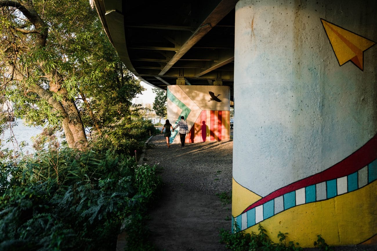 A documentary photograph of a couple walking along the Charles river during a date night engagement session in Boston