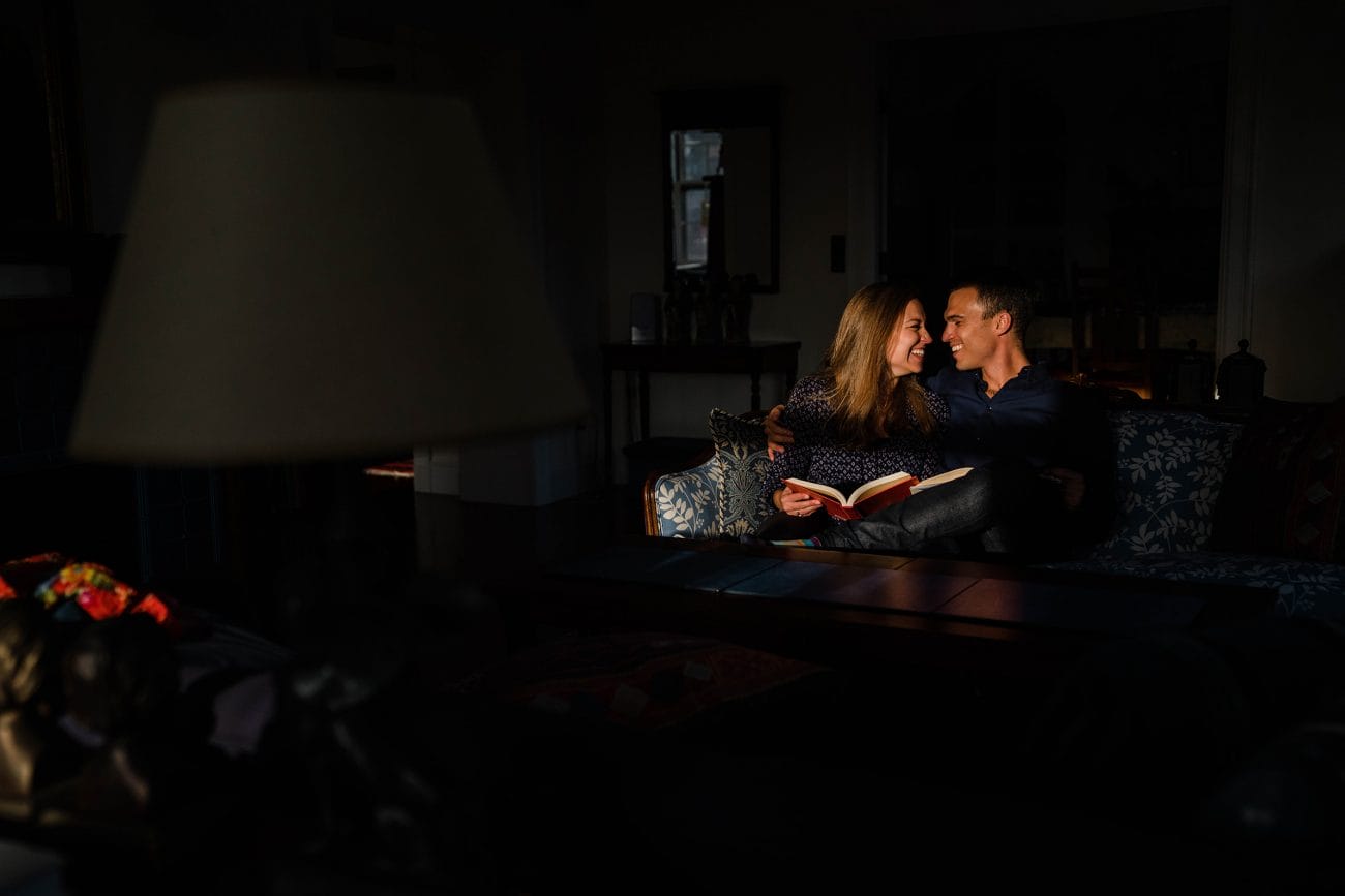 A best of Boston Engagement photograph of a couple laughing together at home while they relax on the couch together.