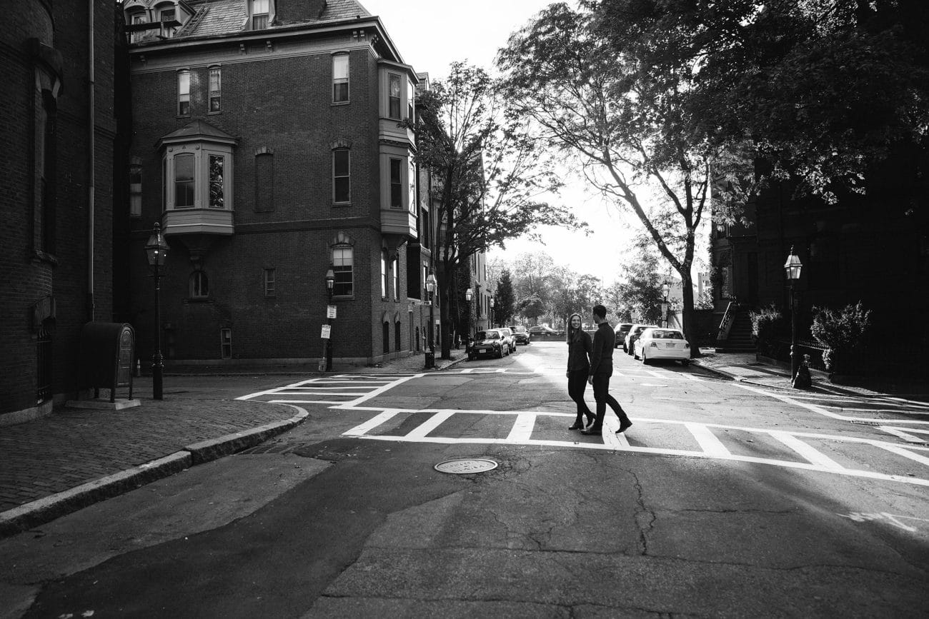 A documentary photograph of a couple crossing the street during their date night engagement session in Boston