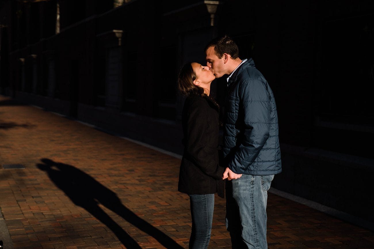 A documentary photograph of a couple kissing during a sunrise engagement session in Boston