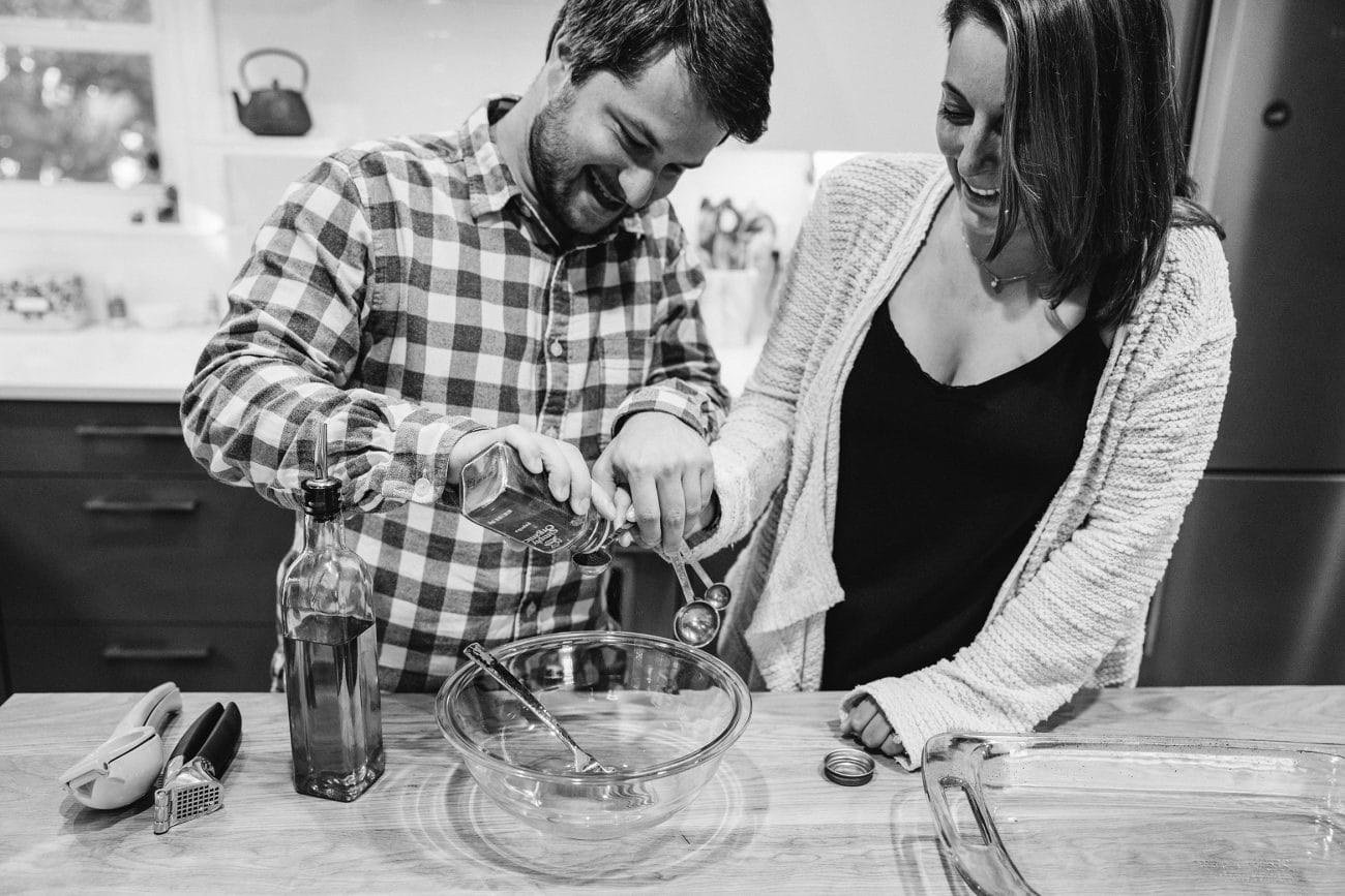 A documentary photograph of a couple cooking together during their in home engagement session in Boston