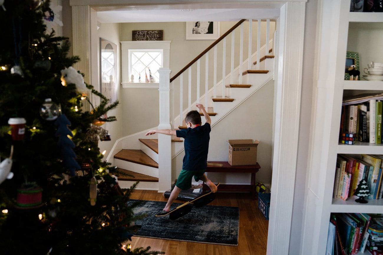 A documentary photograph of a boy playing on his skateboard in the hallway during an in home family session in Boston