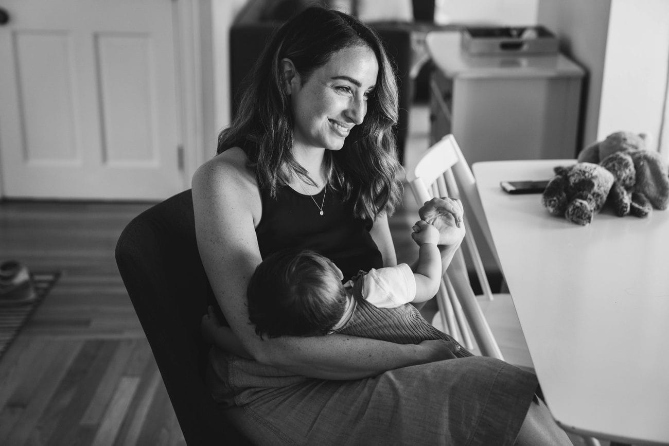 A best of Boston family photograph of a mom smiling at her older son while she nurses her youngest during an in home family session in Boston