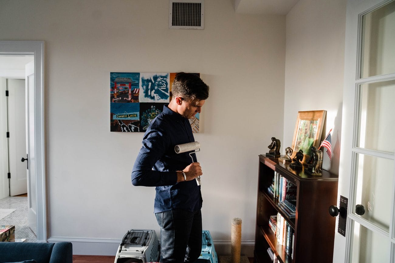 A documentary photograph of a guy removing the lint from his shirt as he finds a book to read during their in home Boston engagement session