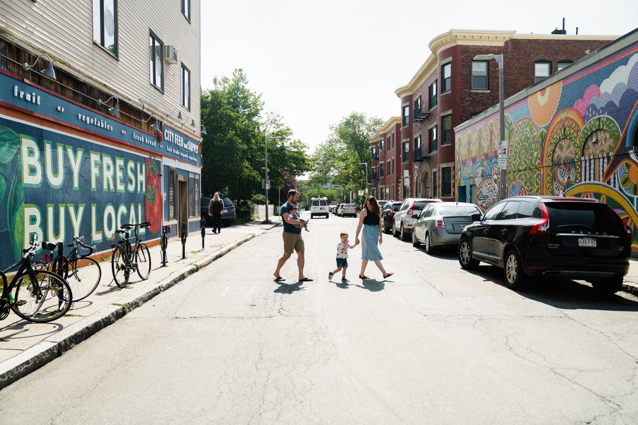 A documentary photograph of a family crossing the street during an in home family session in Boston