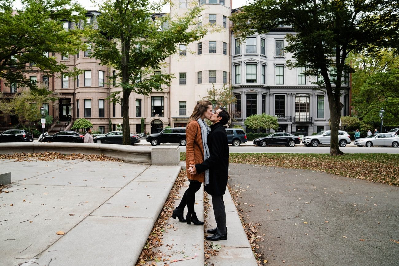 A documentary photograph of a couple kissing on Commonwealth Ave during their date night engagement session in Boston