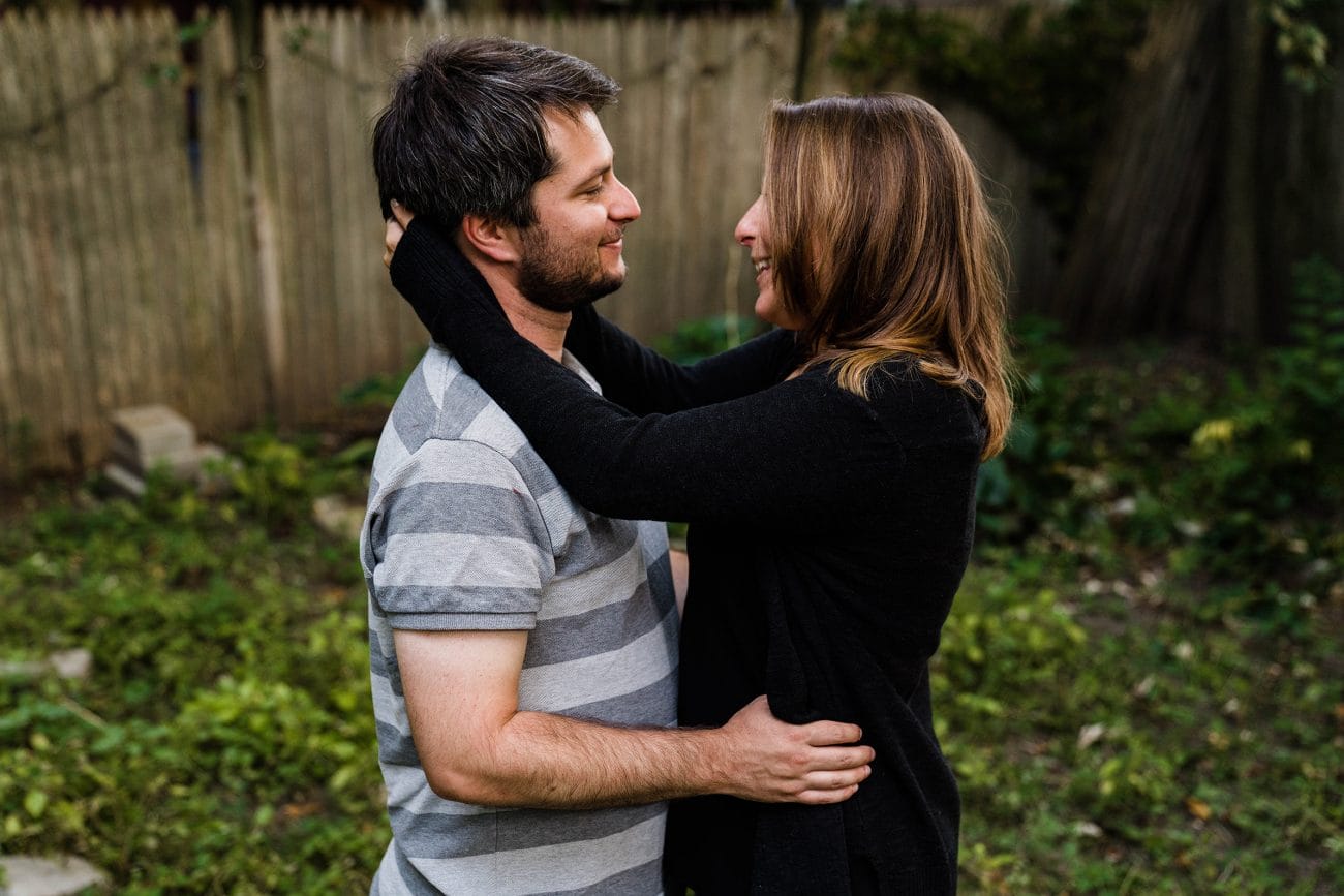 A documentary photograph of a couple sharing an intimate moment in their backyard during an in home engagement session in Boston