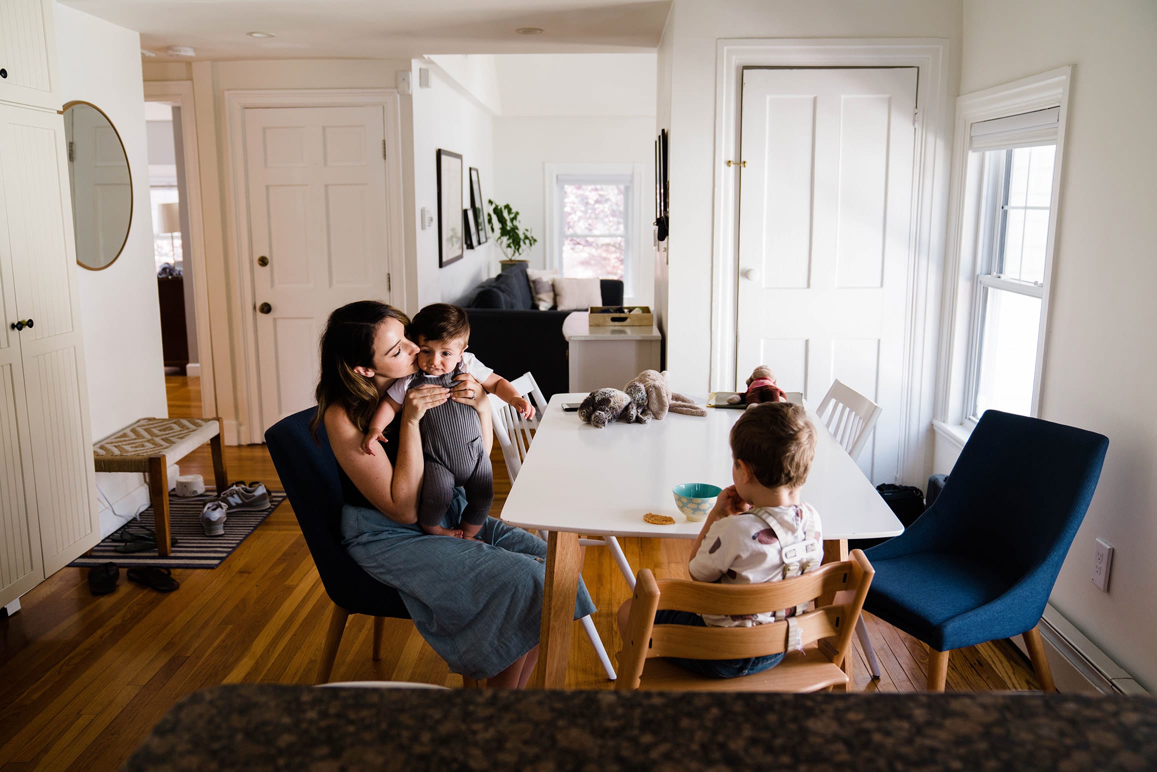 A documentary photograph of a mom kissing her son during snack time at their in home family session in Boston