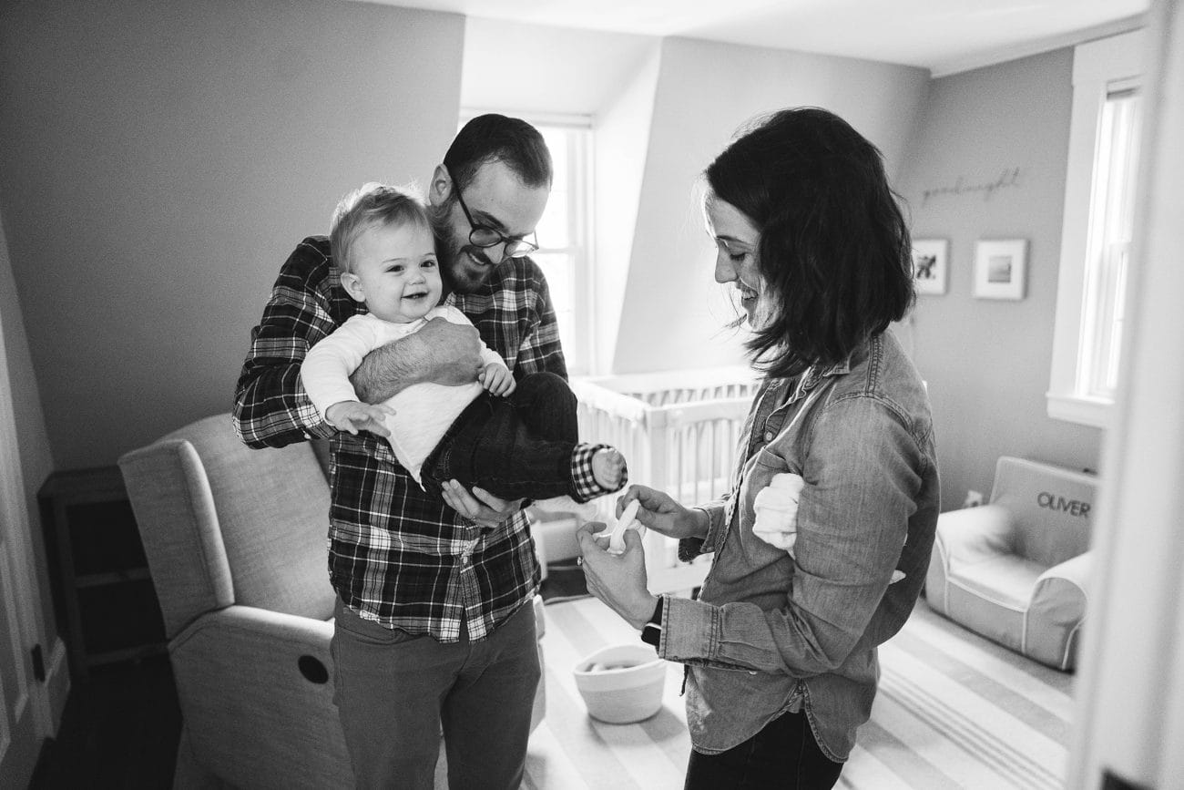 A documentary photograph of parents getting their son dressed during an in home family session in Boston