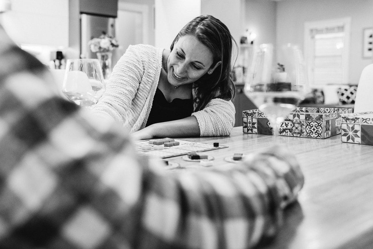A documentary photograph of a couple playing board games during their in home Boston engagement session in Boston