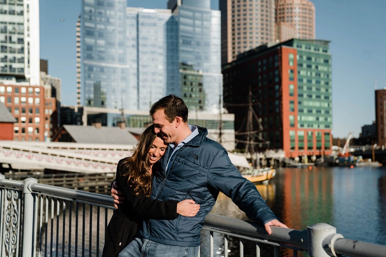 A documentary photograph of a couple  cuddling in the seaport during a sunrise engagement session in Boston