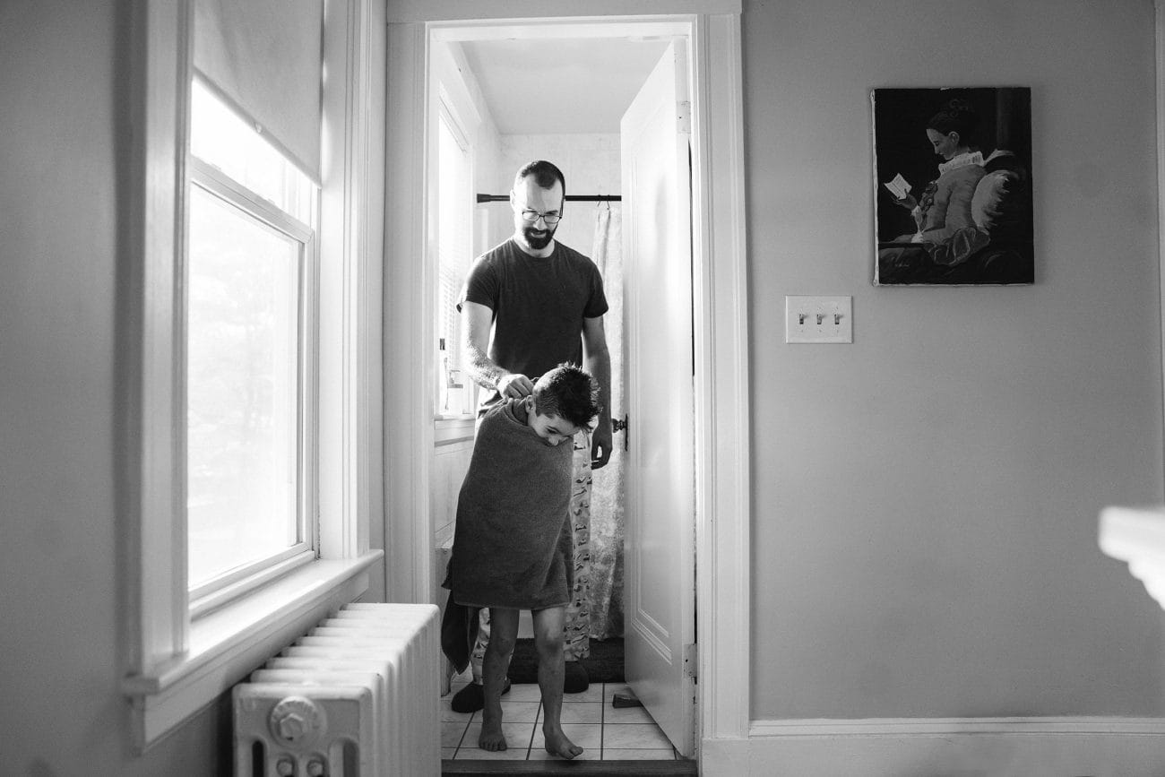 A best of Boston family photograph of a dad helping his son get ready during an in home family session in Boston