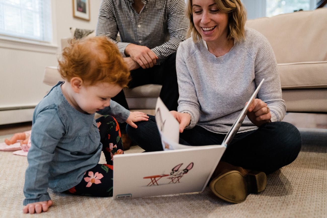 A documentary photograph of a family laughing and reading a book together during an in home family session in Boston
