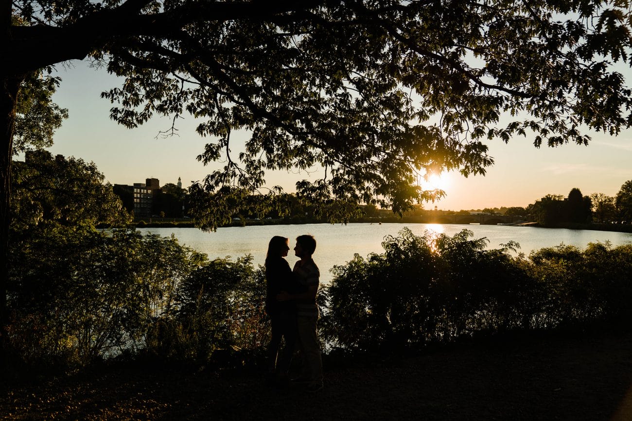 A documentary photograph of a couple sharing an intimate moment near the Charles River during a date night engagement session in Boston