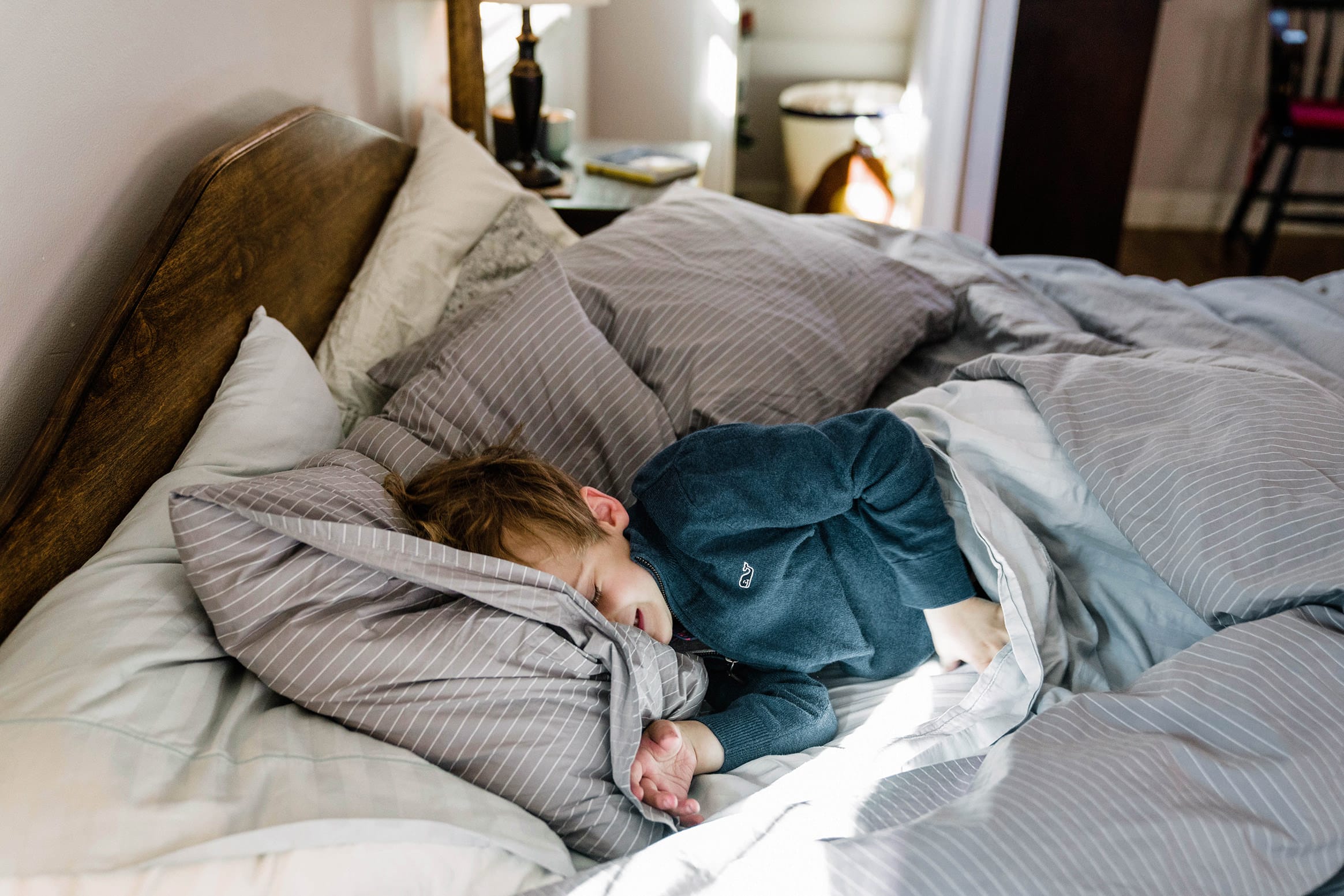 A documentary photograph of a boy sleeping in his parents bed during in home family session in Boston