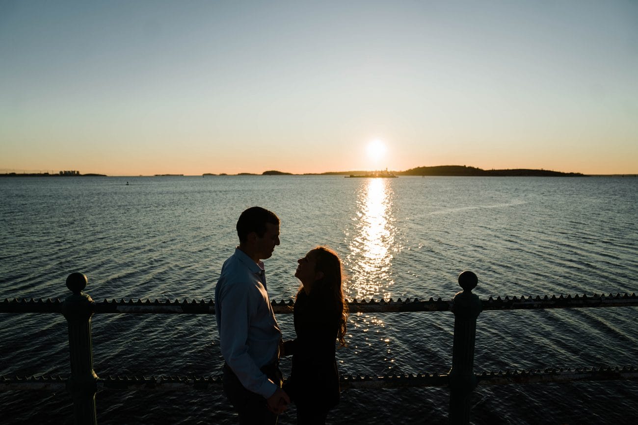 A documentary photograph of a couple sharing an intimate moment during their sunrise engagement session in Boston