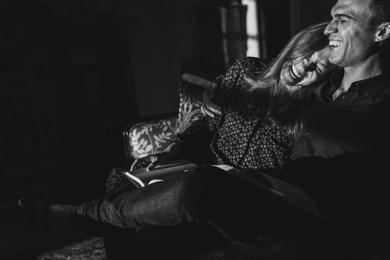 A best of Boston engagement photograph of a couple laughing on their couch together during an in home engagement session in Boston