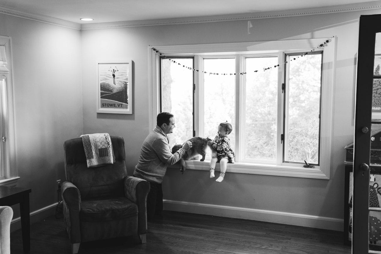 A best of Boston photograph of a father and daughter petting their cat during an in home family session in Boston