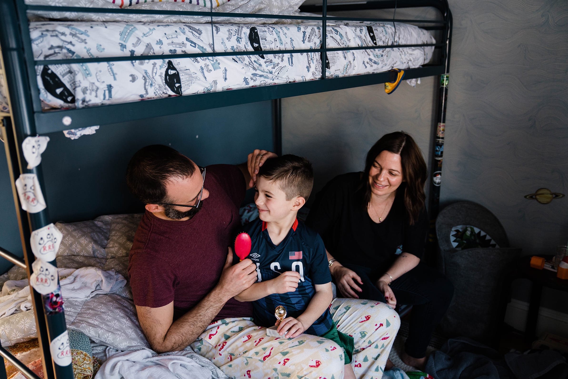A documentary photograph of a father brushing his son's hair during an in home family session in Boston