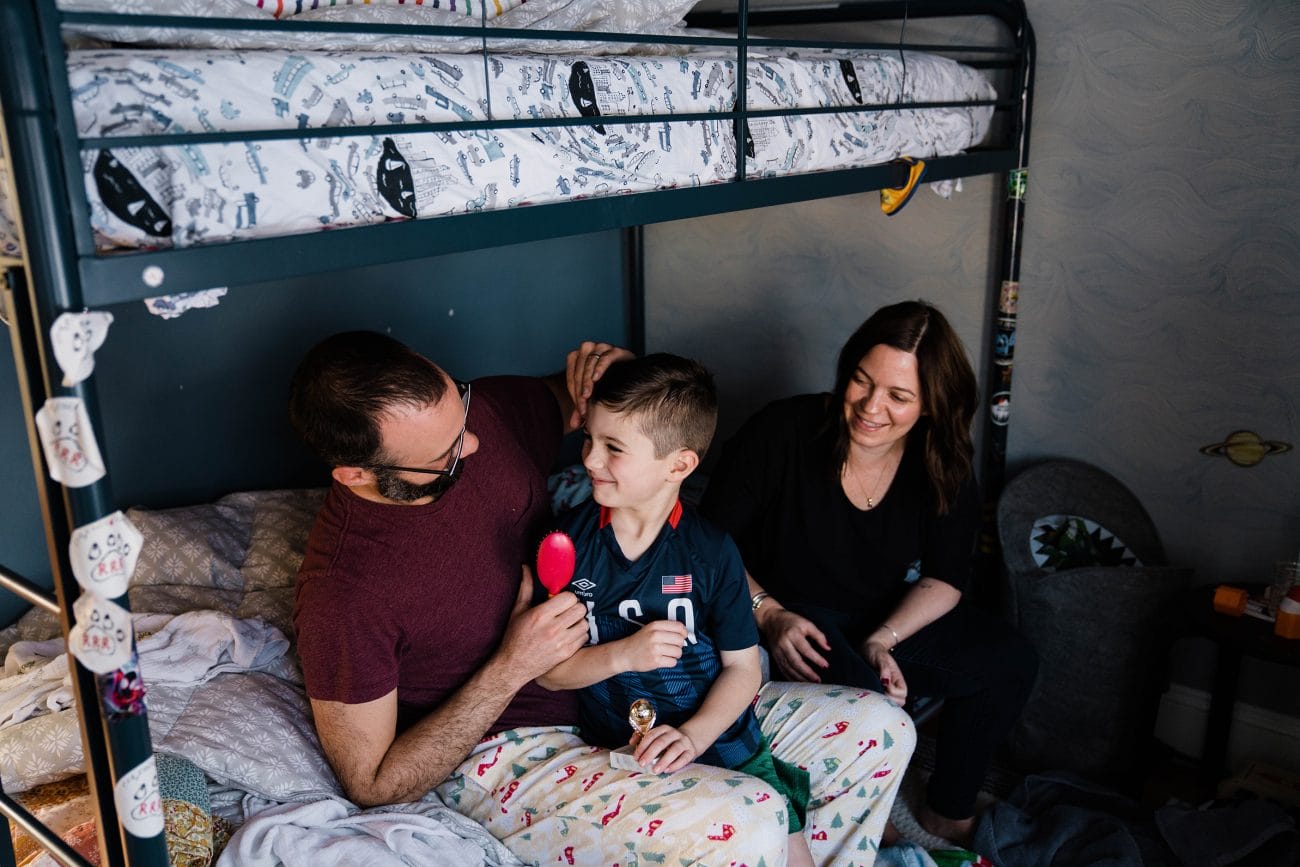 A documentary photograph of a father brushing his son's hair during an in home family session in Boston