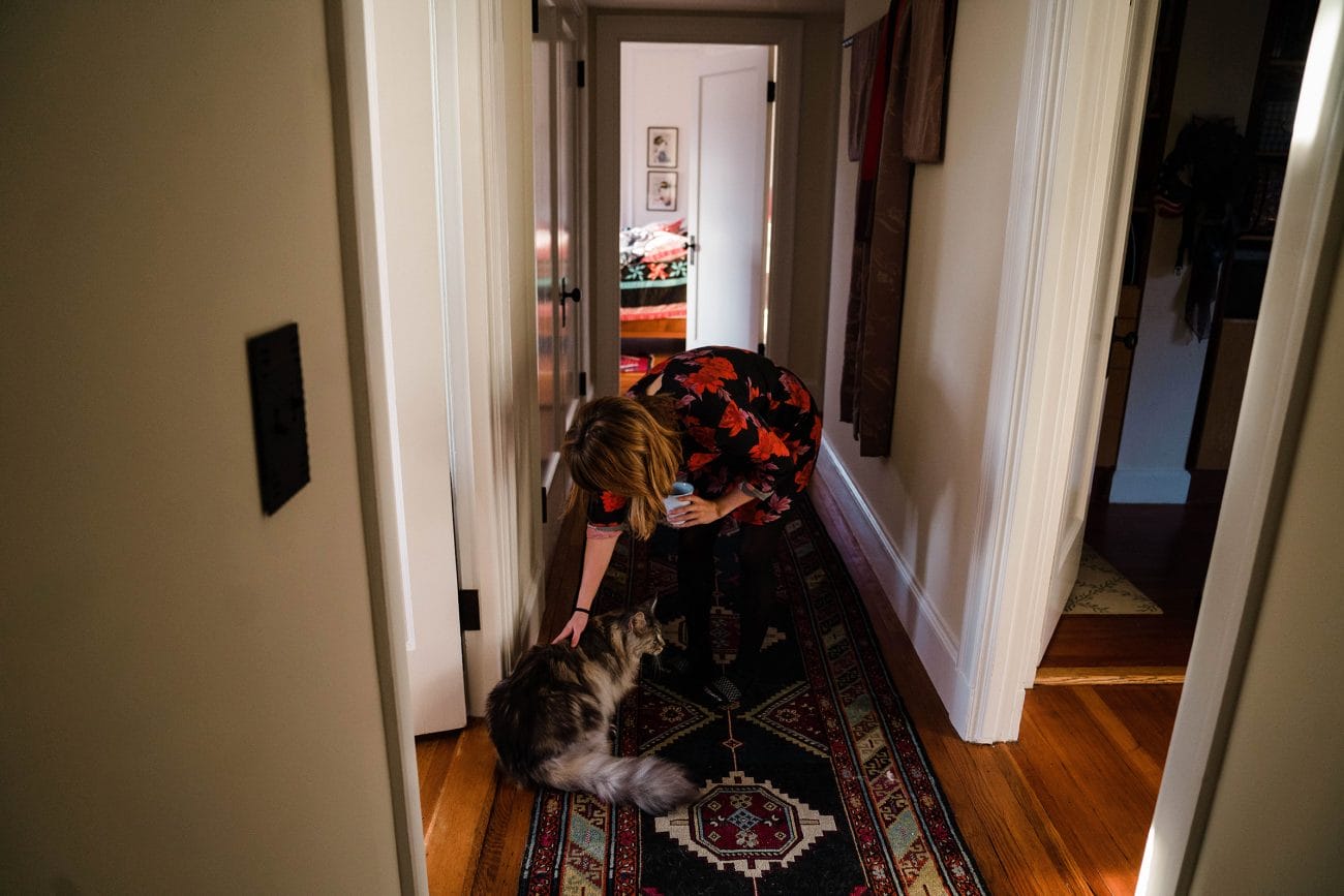 A documentary photograph of a woman petting her cat during an in home engagement session in Boston