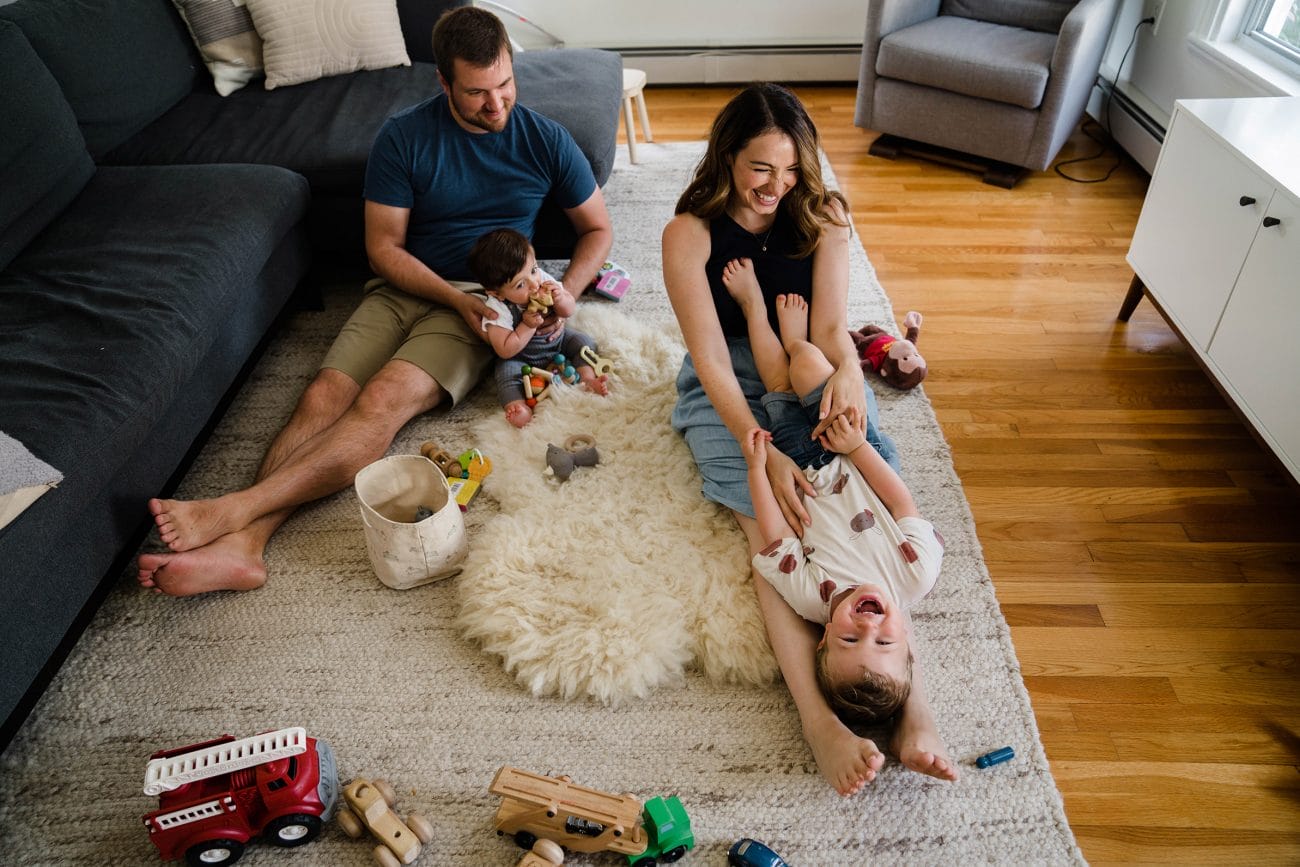 A documentary photograph of a family playing in their living room during an in home family session in Boston