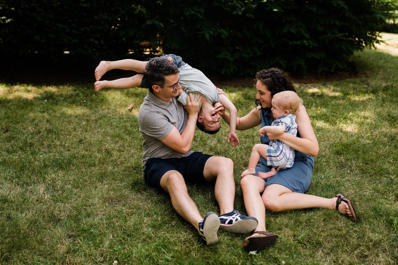 A documentary photograph of a family playing in their yard during an in home family session in Boston