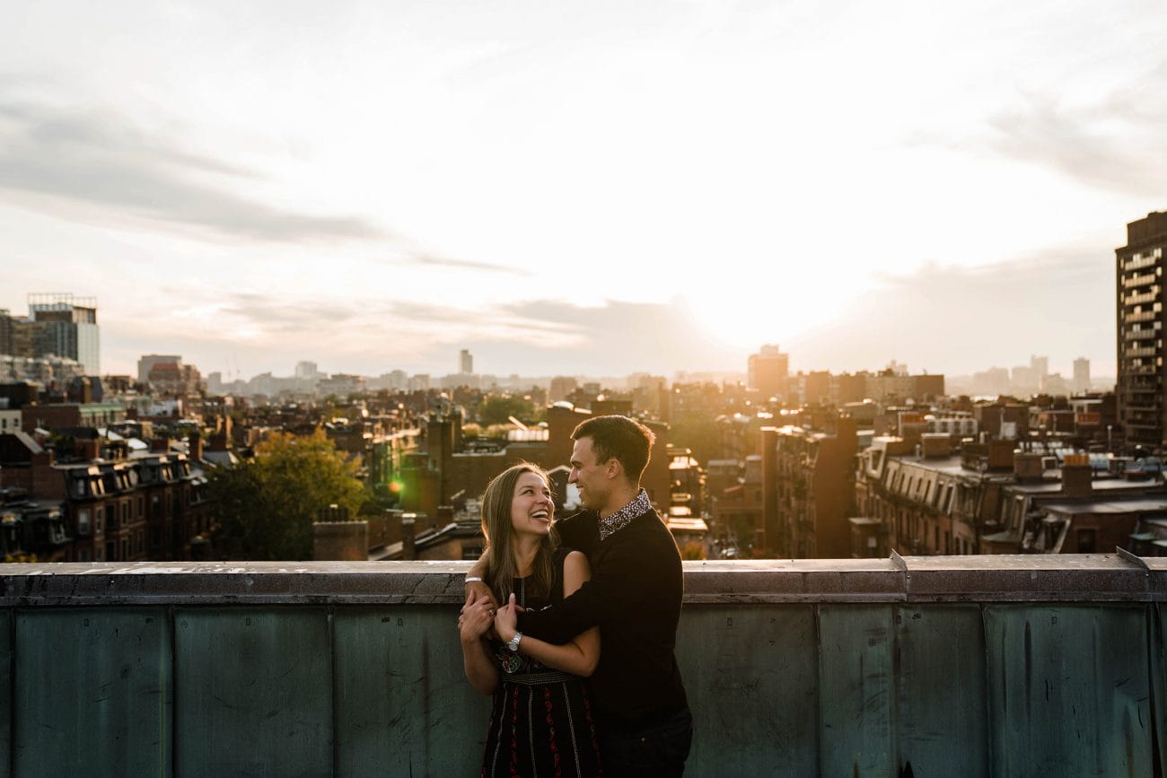 A best of Boston engagement photograph of a couple hugging each other on the roof top during their date night engagement session