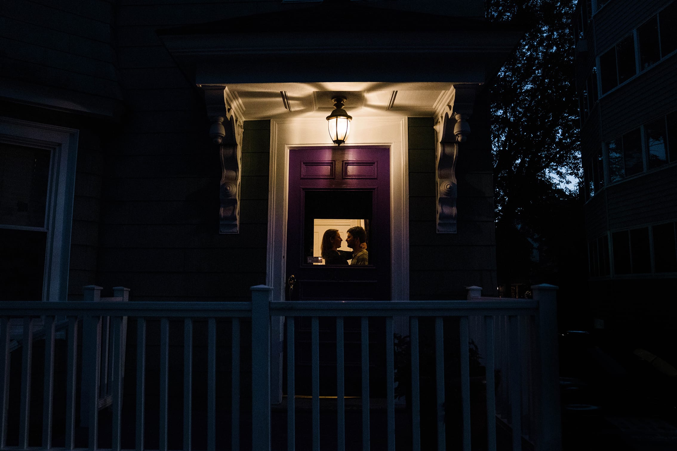 A best of Boston engagement photograph of a couple sharing an intimate moment inside their door after their date night engagement session