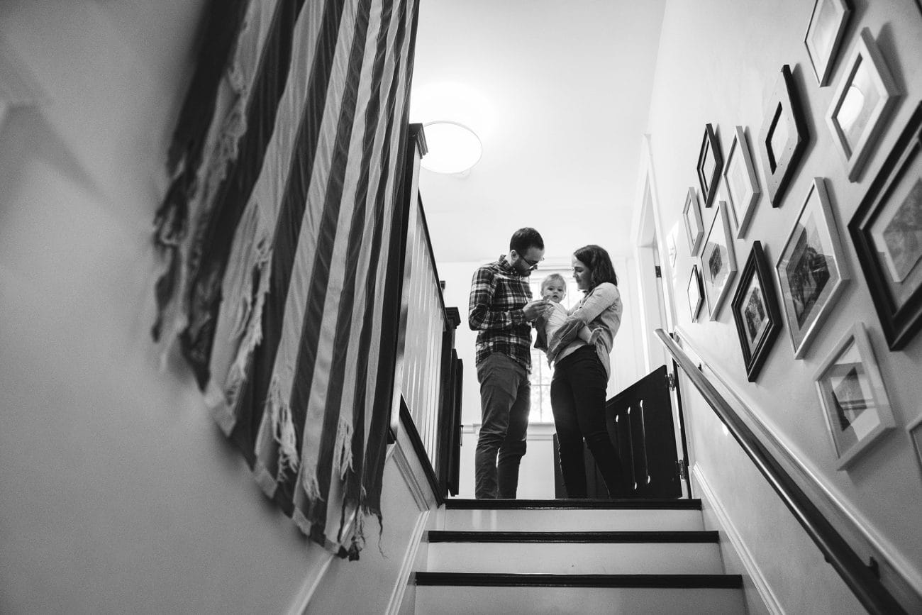 A documentary photograph of a family at the top of the stairs during their in home family session in Boston