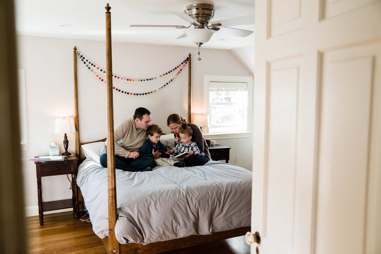 A best of Boston family photograph of a family reading together in bed during an in home family session in Boston