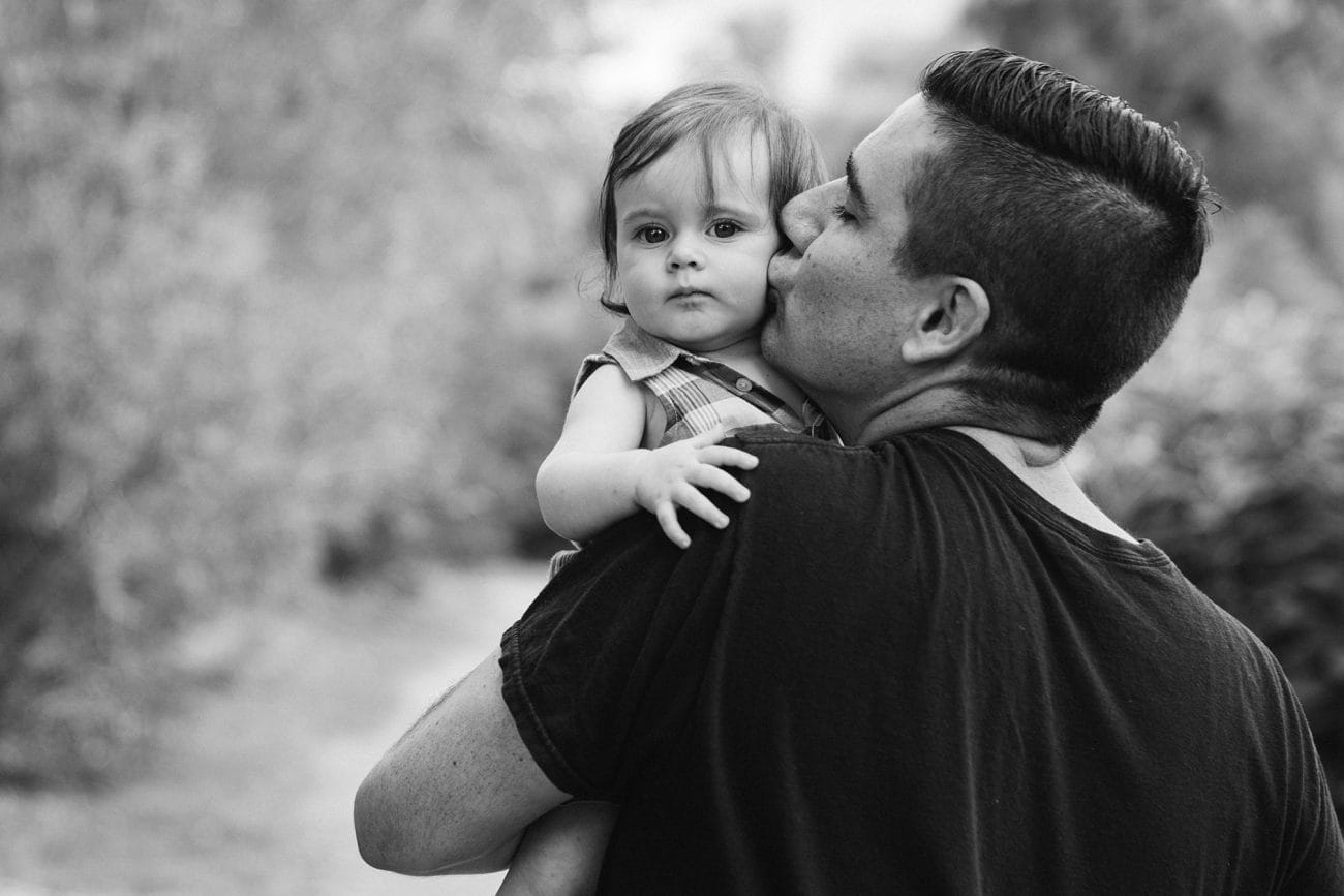 A documentary portrait of a father kissing his daughter during a family session in Boston